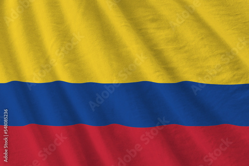 Colombia flag with big folds waving close up under the studio light indoors. The official symbols and colors in banner photo