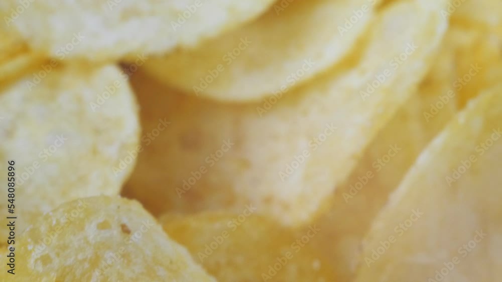 A mountain of potato chips lies on the table. Golden chips close-up. Lots of junk food, macro video. A mountain of potato chips lies on the table. Golden chips close-up. Lots of junk food, macro video.