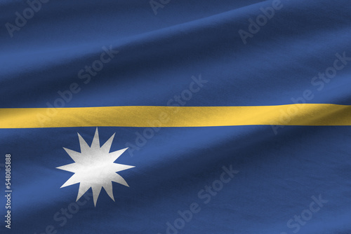 Nauru flag with big folds waving close up under the studio light indoors. The official symbols and colors in banner