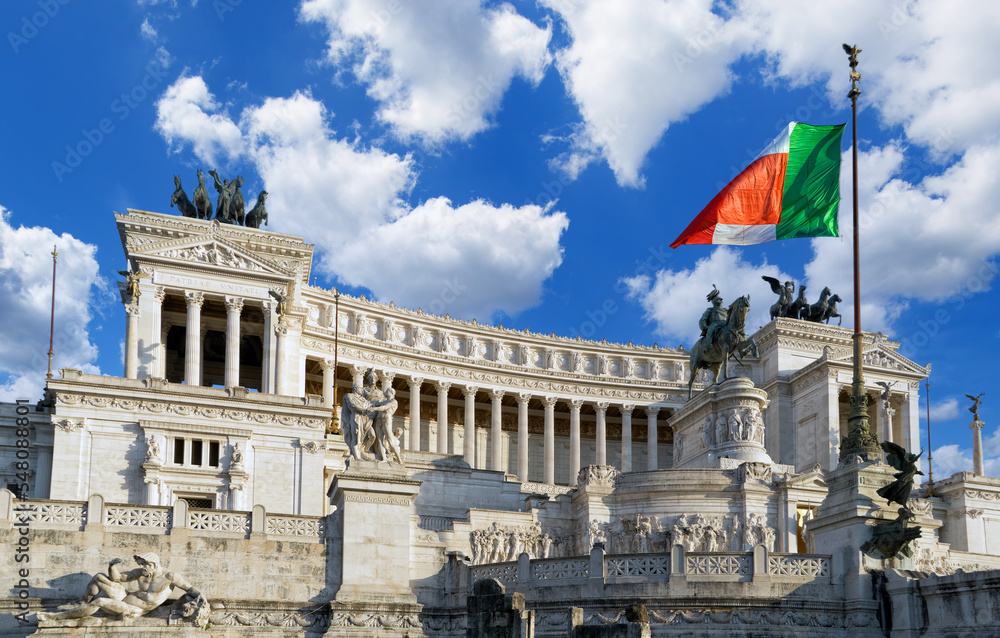 Beautiful view of a Vittoriano - monument in honor of Victor Emmanuel II with a flag of Italy against a blue sky in the sunny day. Rome, Italy 