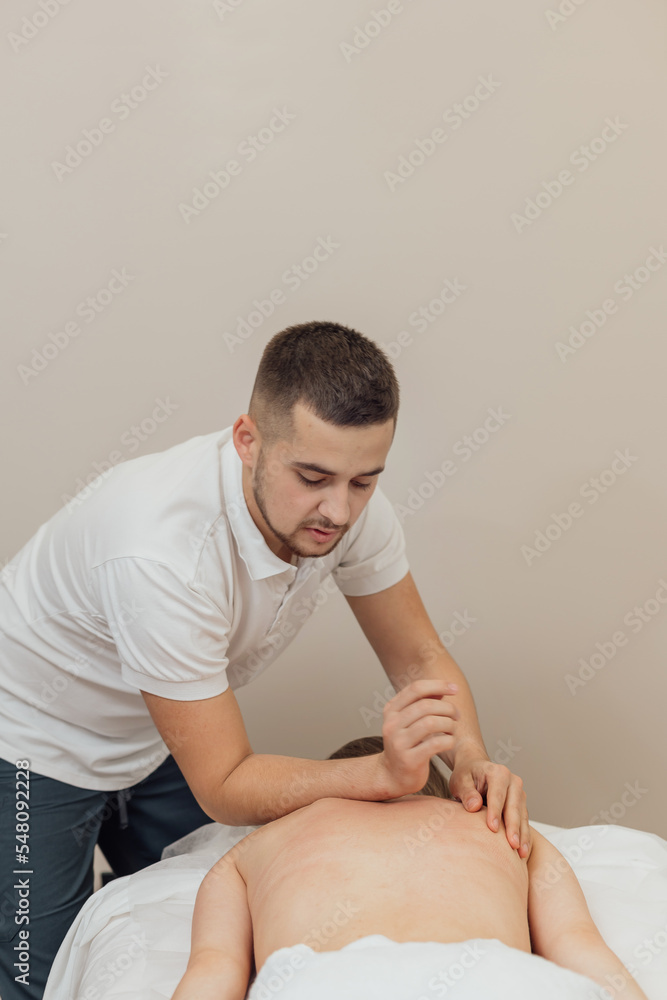 Professional masseur make remedial body massage to a Woman's body lying face down on massage table in spa salon Professional masseur make remedial body massage to a Woman's body lying face down on massage table in spa salon