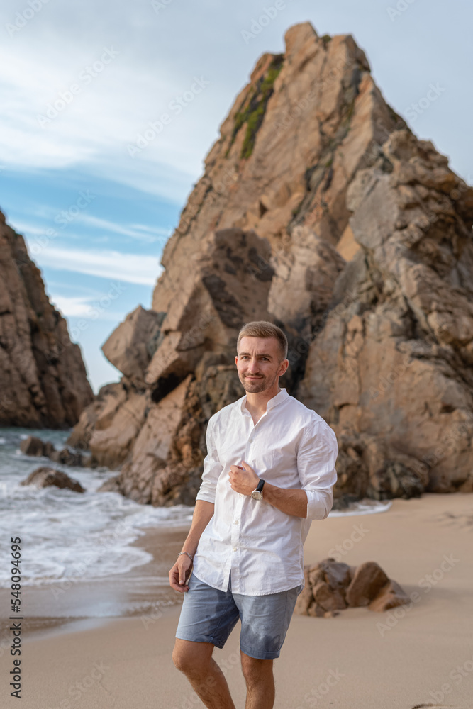 Naklejka premium a stylish guy in a white shirt on the shore of the Atlantic Ocean. business rest