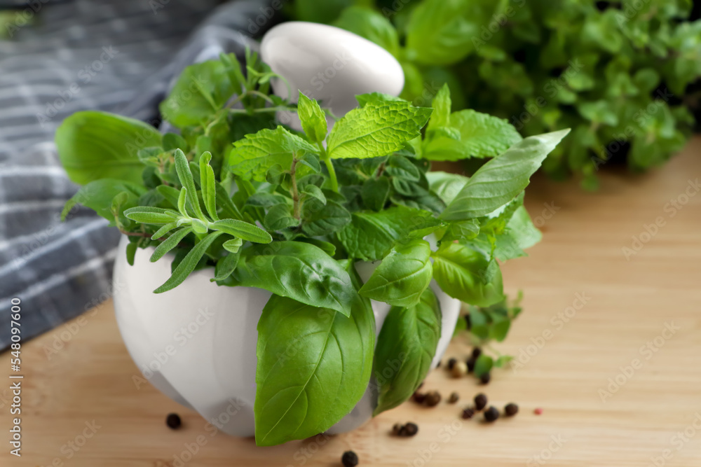 Mortar with different fresh herbs and black peppercorns on wooden table, closeup Mortar with different fresh herbs and black peppercorns on wooden table, closeup