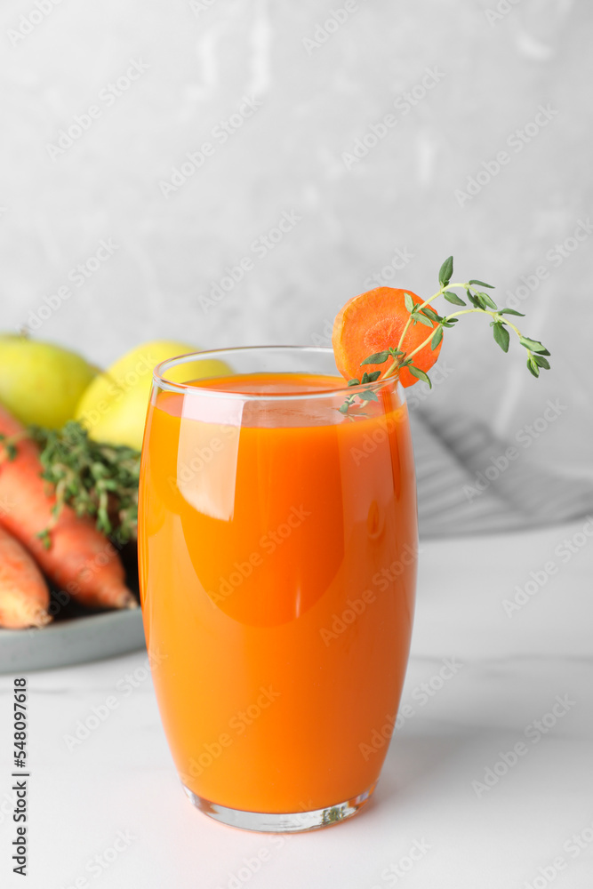 Glass with healthy carrot juice and ingredients on white table Glass with healthy carrot juice and ingredients on white table