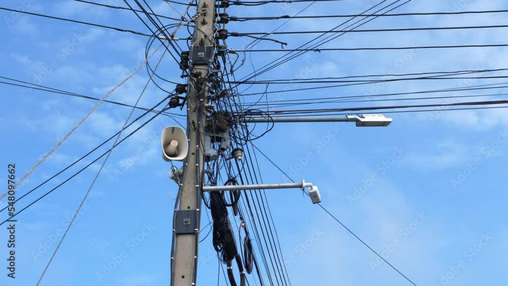 Megaphone or speaker on electric pole with many electric wires in blue white sky background outdoor, and bird fly in the end. Communication, information, technology, advertising concept. Megaphone or speaker on electric pole with many electric wires in blue white sky background outdoor, and bird fly in the end. Communication, information, technology, advertising concept.