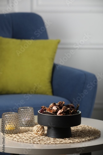 Aromatic potpourri of dried flowers and burning candles on table indoors