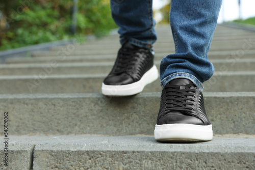Man in stylish black sneakers walking down stairs, closeup