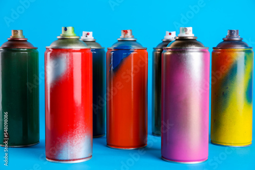 Used cans of spray paints on light blue background