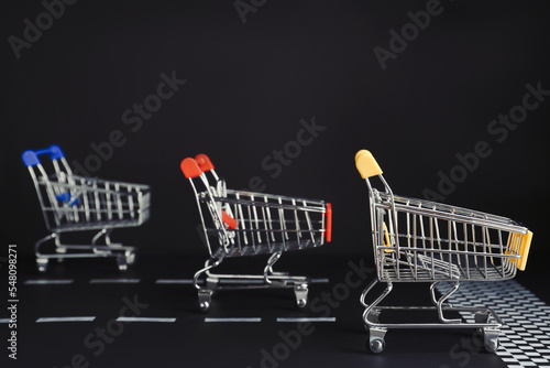 Slika na platnu Competition concept. Shopping carts racing towards finish line