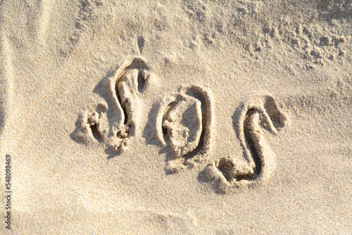 SOS message written on sandy beach outdoors, top view
