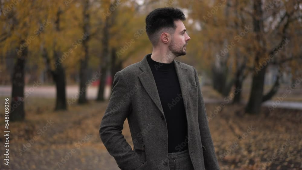 Anxious worried handsome man checking time on watch walking away outdoors. Portrait of stressed nervous Caucasian guy leaving in autumn park. Lifestyle and meetings concept Anxious worried handsome man checking time on watch walking away outdoors. Portrait of stressed nervous Caucasian guy leaving in autumn park. Lifestyle and meetings concept