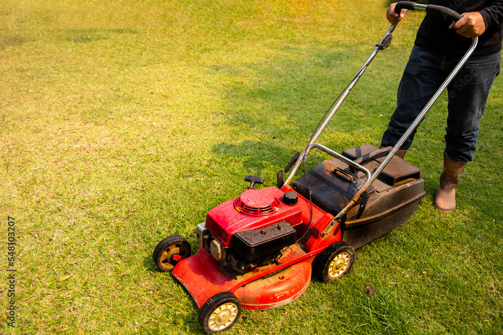 Garden work on the care of the lawn. A man mows the lawn using an electric pushing lawn mower.. cleaning concept. Garden work on the care of the lawn. A man mows the lawn using an electric pushing lawn mower.. cleaning concept.