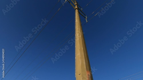 Single electrical tower and power lines against dark blue sky, tilt up, rotate; in Ontario, Canada.