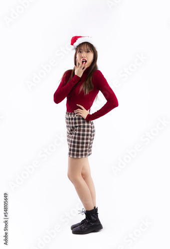 Young asian woman long hair style in red long sleeve t shirt wearing santa hat posing surprised face standing full length on white background. Merry Christmas.