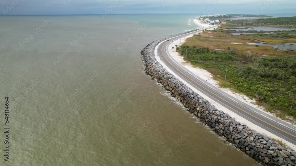 Aerial approach of curved road with waves crashing against rock barrier in Cape San Blas, Florida Aerial approach of curved road with waves crashing against rock barrier in Cape San Blas, Florida