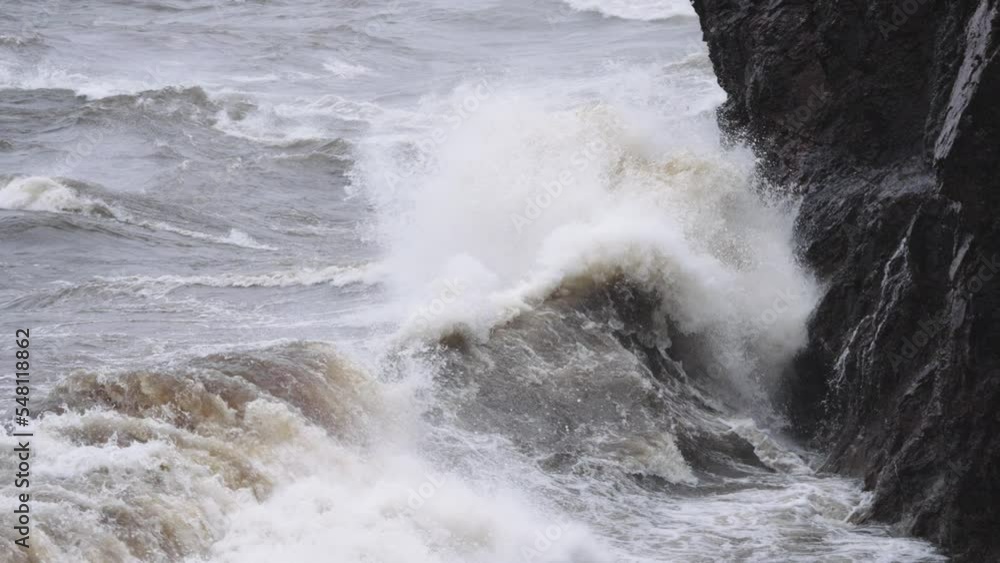 Rough waves during a storm crashing onto rocky coastal cliffs in slow motion Rough waves during a storm crashing onto rocky coastal cliffs in slow motion