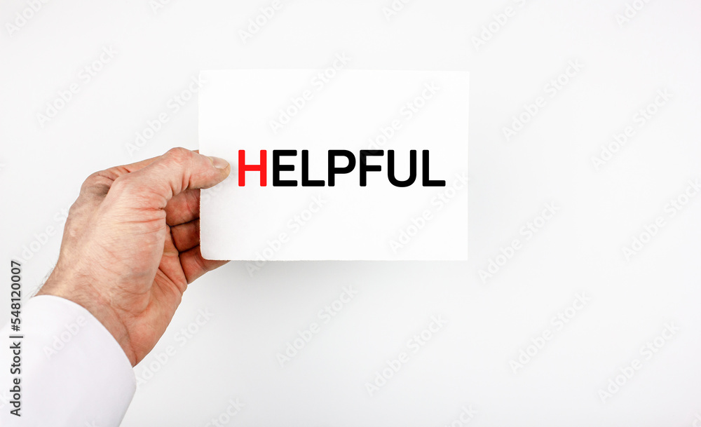 Helpful writing on the sheet. Man's hand holding a sheet with a note HELPFUL Helpful writing on the sheet. Man's hand holding a sheet with a note HELPFUL
