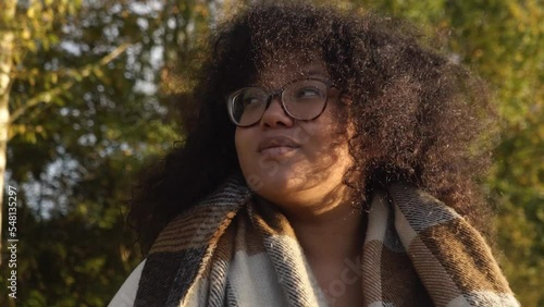 Smiling Black woman with curly hair portrait video in autumn forest. slow motion shot.