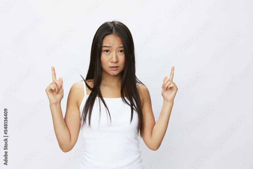 Asian woman hand signals, finger pointing facial skin problems, acne and inflammation, red rash and allergies, chicken pox, sadness from rashes. Facial skin care concept for diseases and nerves Asian woman hand signals, finger pointing facial skin problems, acne and inflammation, red rash and allergies, chicken pox, sadness from rashes. Facial skin care concept for diseases and nerves