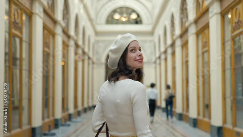Young Parisian woman in a white beret walking in a gallery