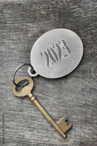 2023 engraved on a ring of an old golden key on rustic wooden © coco