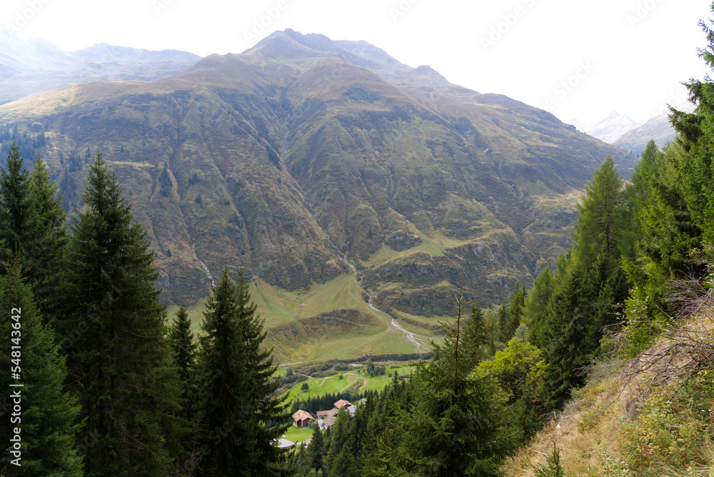 Alp with cabins in the Swiss Alps at region of Swiss mountain pass Oberalppass on a blue cloudy late summer day. Photo taken September 5th, 2022, Oberalp Pass, Surselva, Switzerland.