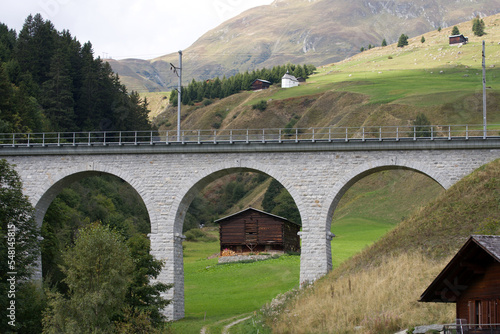 Scenic view of railway viaduct with mountain panorama in the background at mountain village Dieni, Canton Graubünden, on a summer day. Photo taken September 5th, 2022, Dieni, Surselva, Switzerland. photo