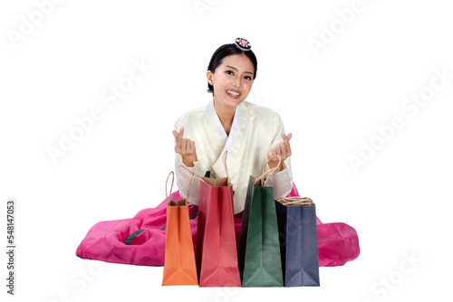 Asian woman wearing a traditional Korean national costume, Hanbok, sitting and showing shopping bags