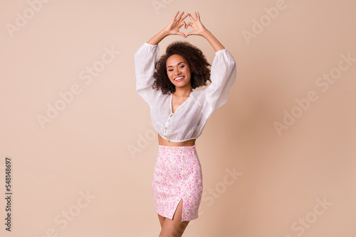 Portrait of pretty positive lady hands fingers showing heart gesture above head isolated on beige color background