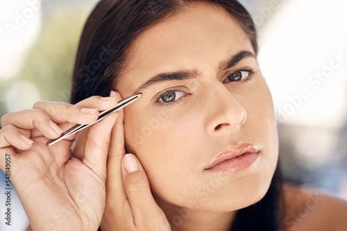 Photos Woman in mirror plucking eyebrows with tweezers and grooming facial routine in morning