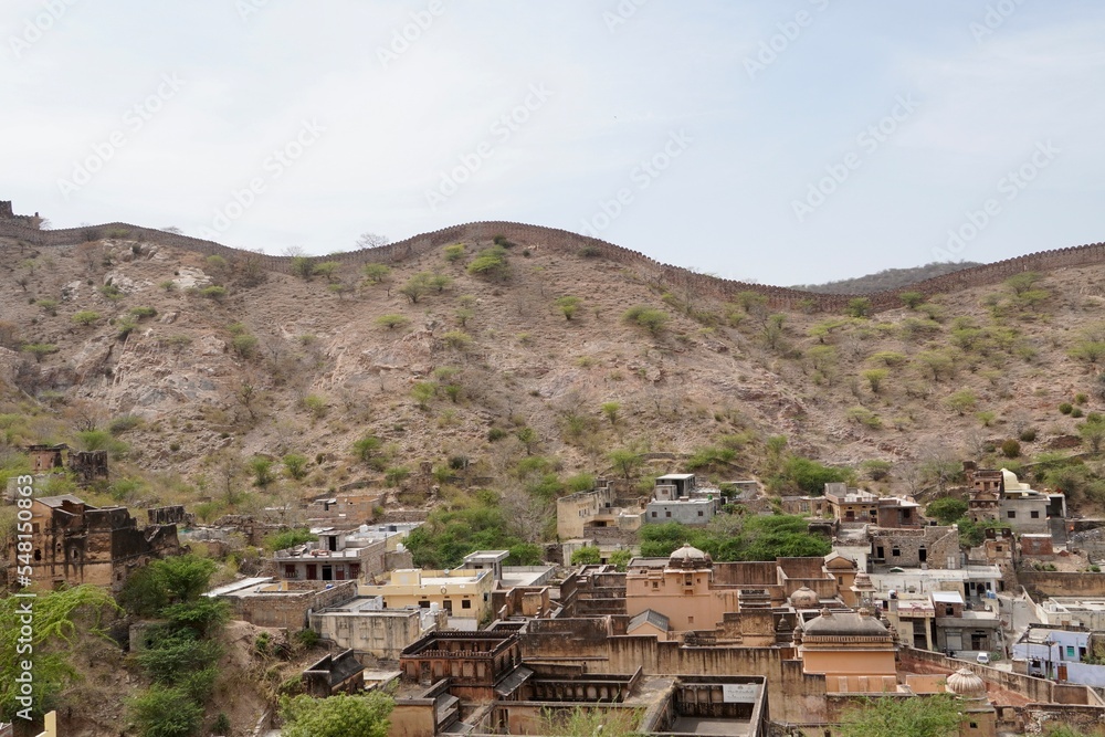Village in the mountains. Houses laid on high mountain on summer afternoon at Jaipur, India. Scenic view of mountain houses against sky.