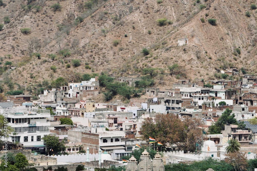 Village in the mountains. Houses laid on high mountain on summer afternoon at Jaipur, India. Scenic view of mountain houses against sky.