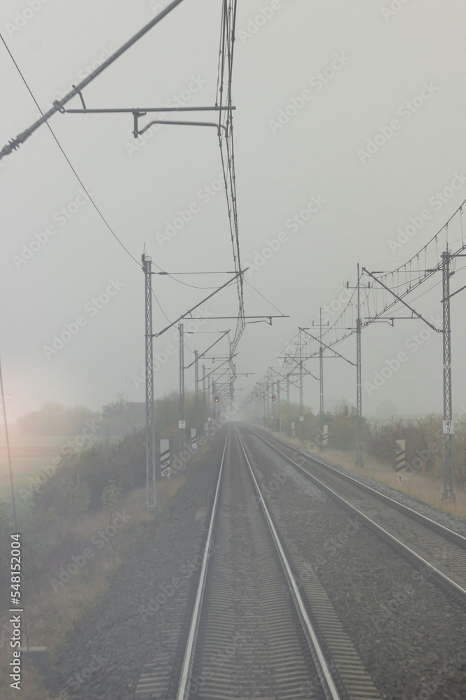 Autumn railway tracks and traffic signals in a foggy morning. View from the last car of the train. Tourism concept.