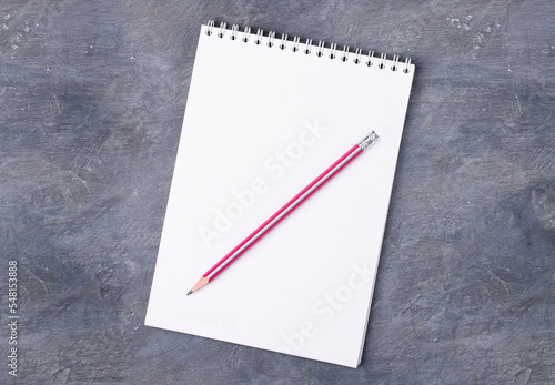 Empty paper white notepad and pink pencil on gray concrete background