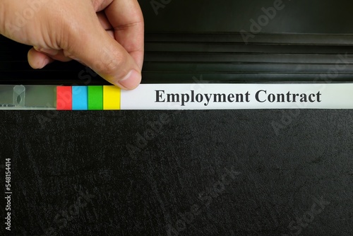 Hand picking employment contract file in black binder folder. Human resources concept.
