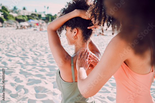 Woman, friends and back sunscreen at the beach for healthy skincare, protection or moisturizer in the outdoors. Hands of female helping friend apply SPF, sunblock or lotion in care for health or skin