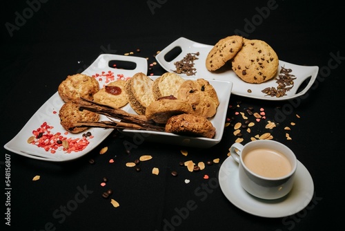 Top view of cookies on white plates with a cup of coffee on a black background