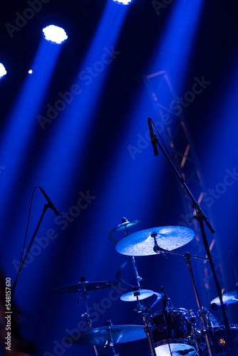 A drums et on stage with microphones pointed at it in blue moody lighting