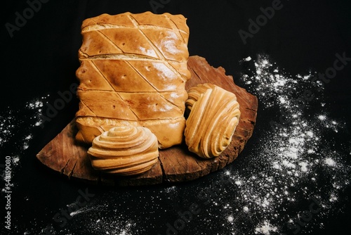 Top view of a wooden board with sweet puff pastry buns on a black background