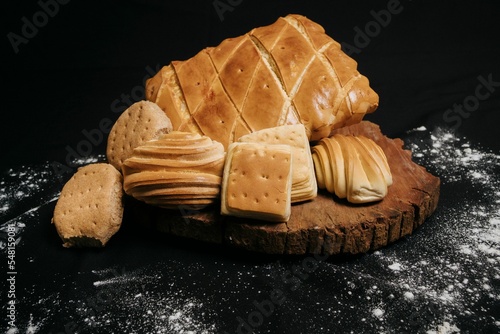 Close-up of a wooden board with sweet puff pastry buns on a black background
