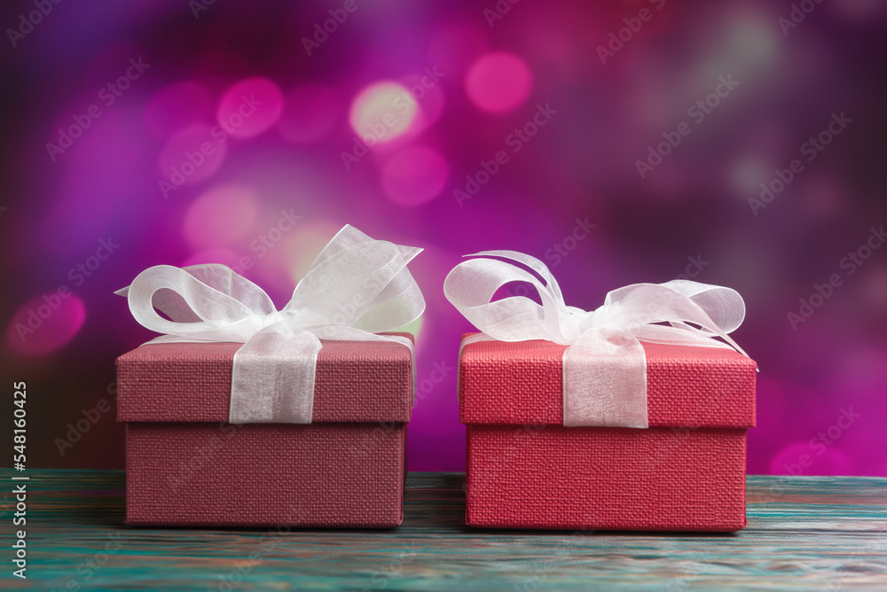 Two gift boxes with white bows over defocused Christmas lights. New Year and Xmas card concept Two gift boxes with white bows over defocused Christmas lights. New Year and Xmas card concept