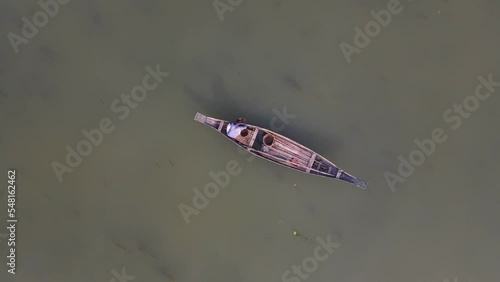 Aerial Birds Eye View Of Lone Fisherman On Traditional Wooden Boat Floating On The Ichamati River. photo