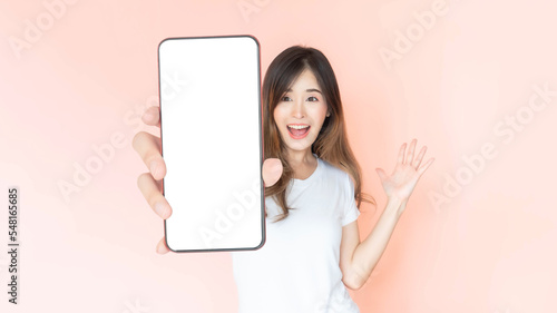 beautiful Asian young woman showing big smart phone with blank screen , white screen empty copy space for advertising banner isolated on pink background , Mock Up Image © suphaporn