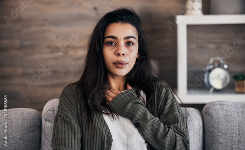 Anxiety, worry and woman breathing on sofa to relax, calm down and stress relief from panic attack. Mental health, depression and portrait of anxious girl sitting on couch with hand on chest in pain photo