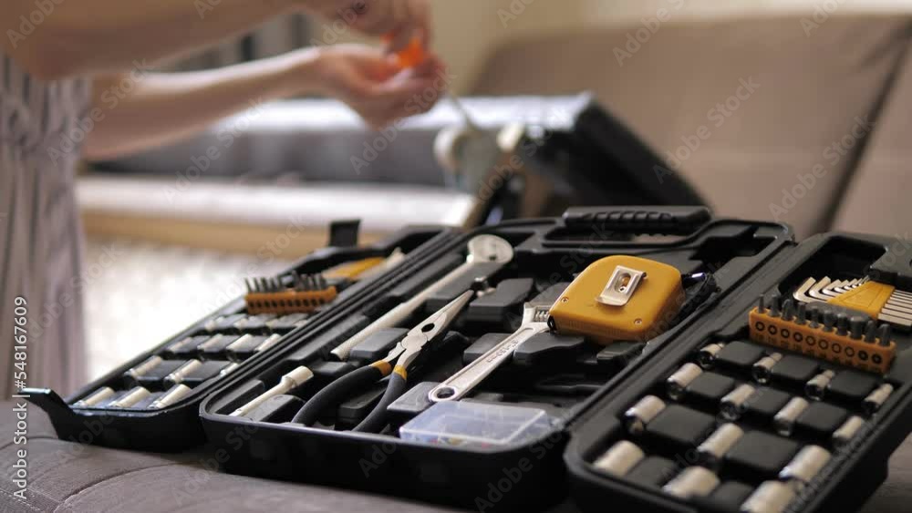 Young girl disassembles the sofa with a screwdriver on the background of set of tools. Heavy assembly of home furniture by yourself. Restoration of soft furniture. Stretching soft furniture at home. Young girl disassembles the sofa with a screwdriver on the background of set of tools. Heavy assembly of home furniture by yourself. Restoration of soft furniture. Stretching soft furniture at home.