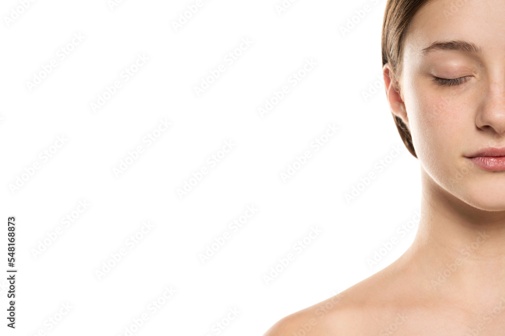 Half portrait of a beautiful young women with tied hair closed eyes and no makeup on a white background. Half portrait of a beautiful young women with tied hair closed eyes and no makeup on a white background.