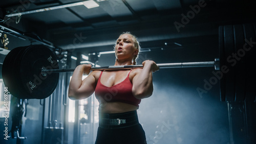 Obraz na płótnie A Focused Female Bodybuilder Lifts Barbell with Heavy Weights in a Hardcore Gym Workout