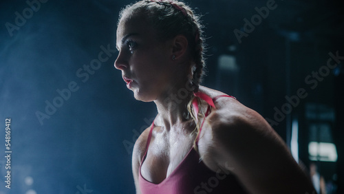 An Energetic Female Athlete Running in Place as a Cardio Exercise for Daily Workout in a Dark Gym. An Agile Future Roadrunner Training Hard For the Next Competition