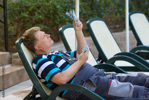 The worker recalculates the received remuneration for work, lying on a sun lounger by the pool. photo