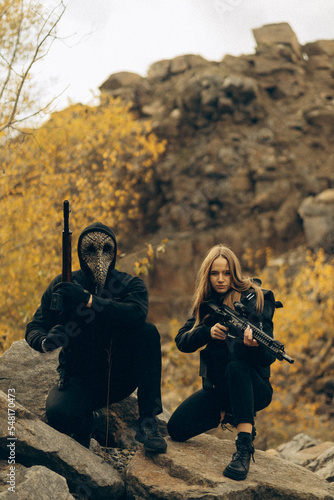 Guy and girl special forces in mask and with machine gun among mountains.